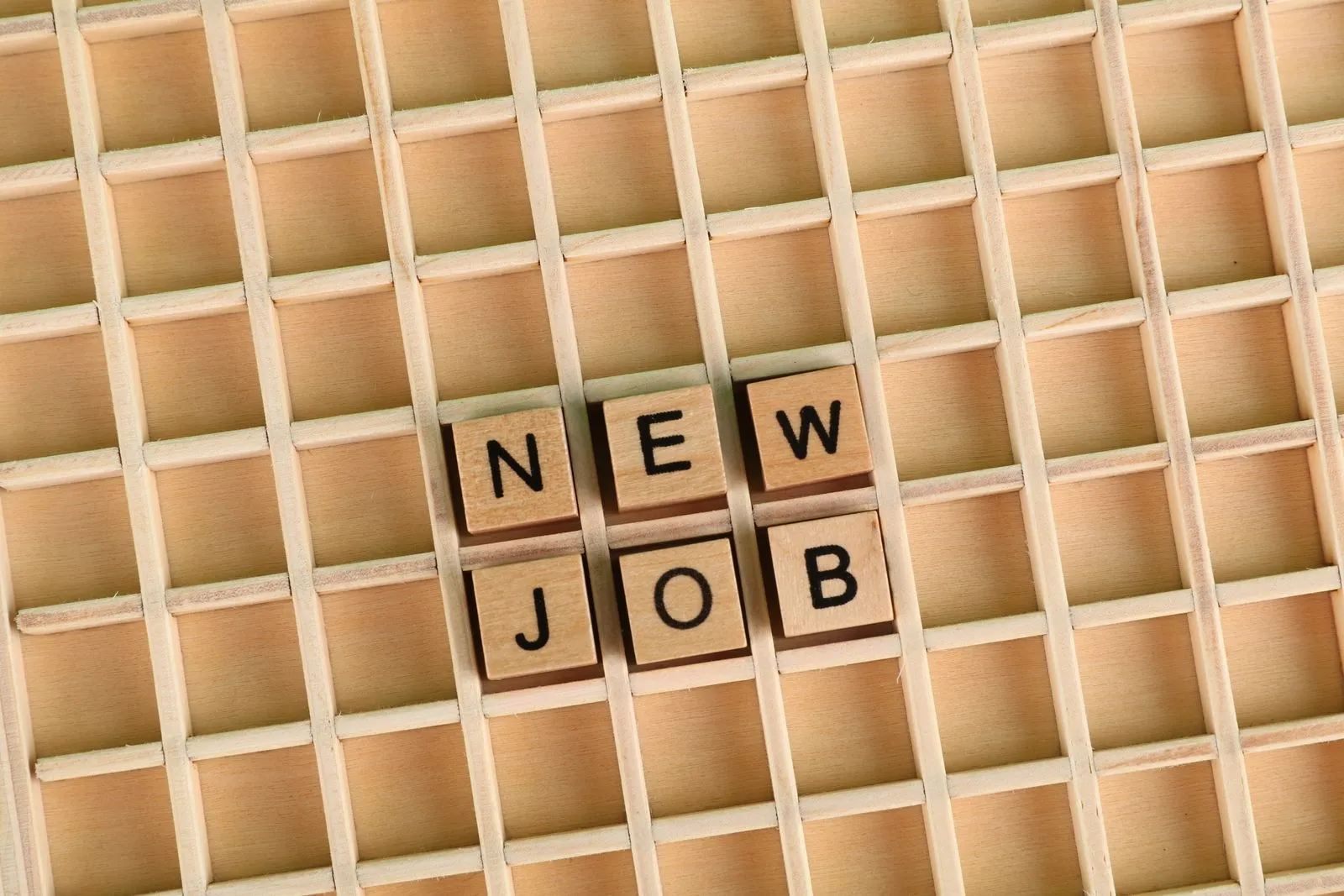 Wooden tiles spelling NEW JOB — the payoff of applying early