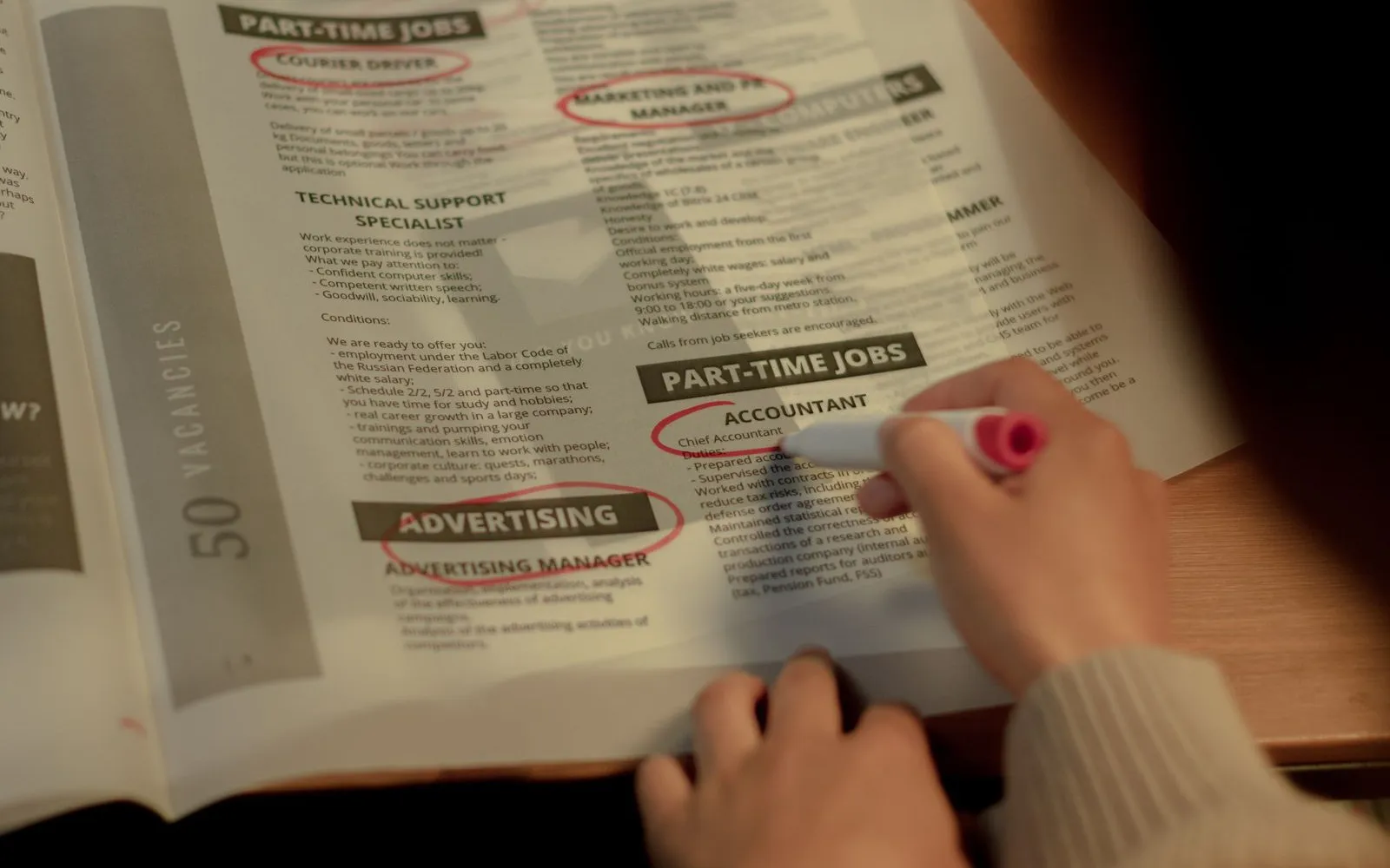Job seeker marking job listings in a newspaper — many of which may no longer be real openings